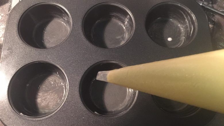 法式乳酪月饼,把拌好的饼皮糊装入裱花袋里,模具刷上一层黄油
