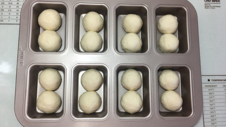 白面包小吐司,醒发结束后再揉圆,放入模具中,每个格子放入两个小面团,然后放入烤箱中用发酵菜单进行二次发酵,时间为30分钟左右。