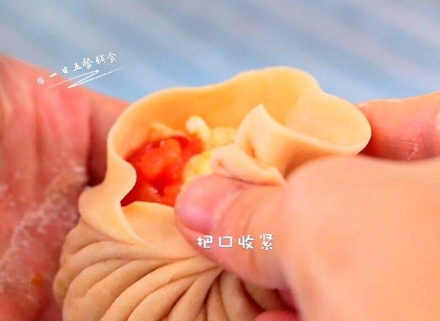 番茄鸡蛋馅饼,像包包子一样,捏褶子,把口收紧,褶子一面朝下放入锅中。