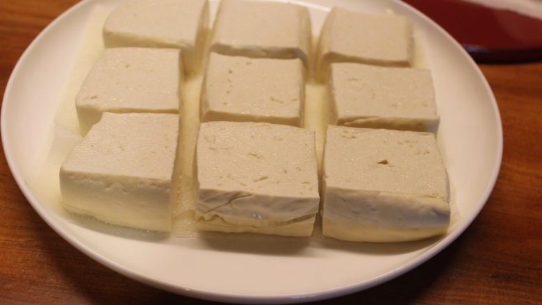 青酱烤豆腐,压好的豆腐,纸巾上吸满了水分,豆腐变的较为结实有弹性。先分切成小块比将一大块豆腐去压更容易压出水分和保持形状。