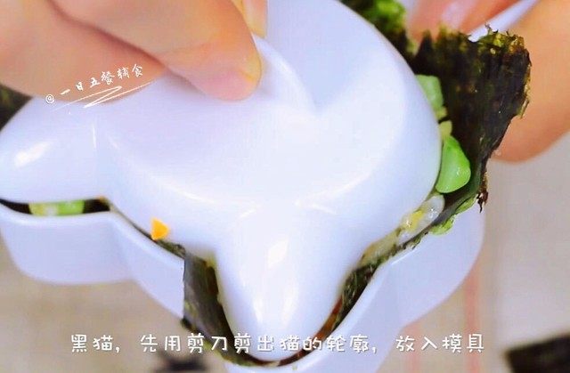 杂蔬鳕鱼猫饭团,再来做一只黑猫，用剪刀在海苔上剪出猫的轮廓，将海苔放入模具，接着放入米饭，压出猫的形状后将黑猫倒扣在盘子里。