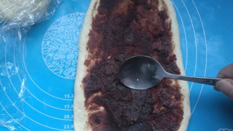 扭扭豆沙小土司,擀成长的椭圆形,机上豆沙馅,用小勺子铺平。