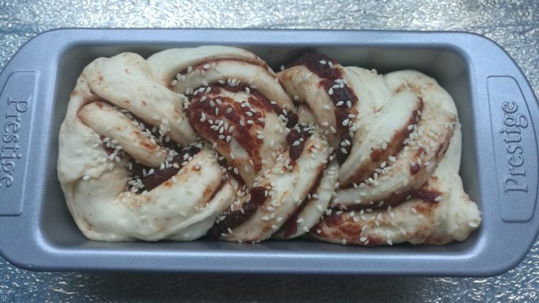 扭扭豆沙小土司,面包批发酵到2-3倍大,取出,撒上适量芝麻,烤箱预热上下火180度10分钟。