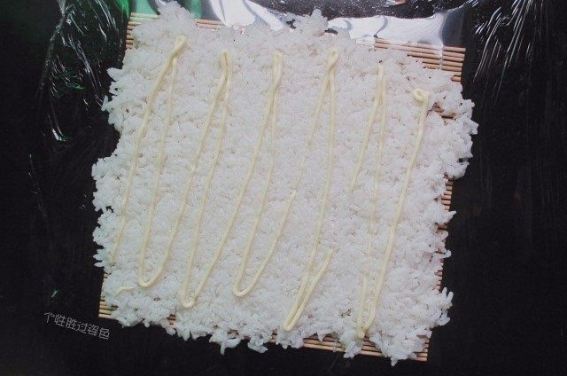 手卷饭团,用饭铲把米饭进行调整铺平,挤上沙拉酱