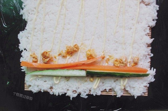 手卷饭团,放入腌好的黄瓜条胡萝卜条,咸蛋黄稍稍掰碎放入