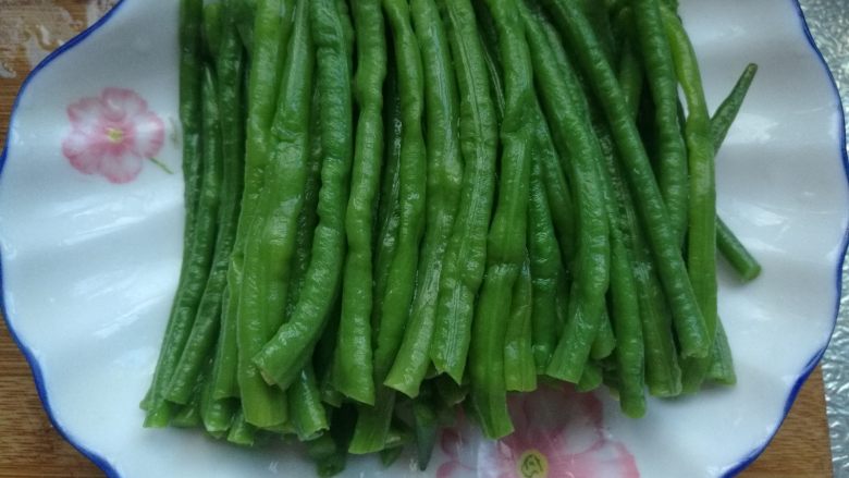 麻酱拌豆角,捞出豆角放案板上切成长短相同的段,放入盘内。
