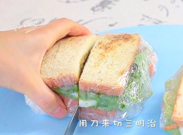 牛油果鸡蛋火腿三明治,准备切了。因为有了保鲜膜切的时候,中间的食物不会掉。吃的时候也很方便!