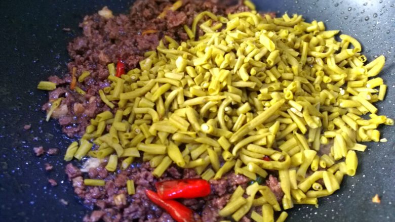 酸豆角炒牛肉末,将备干水份的酸豆角倒入牛肉中。