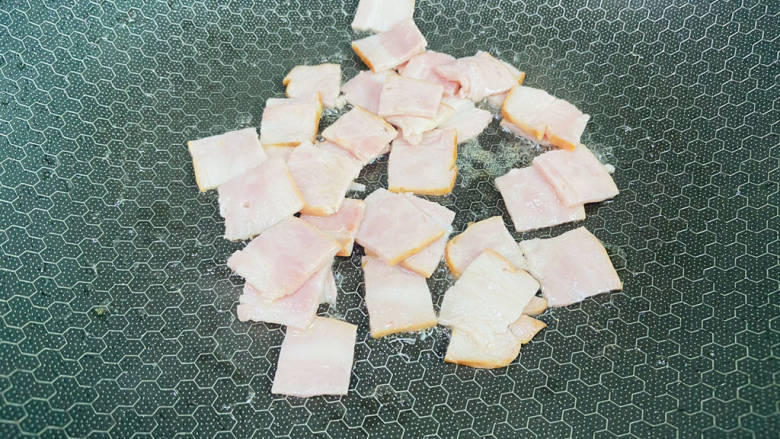 培根炒秋葵,锅中加入少许食用油加热至七成热,放入培根小火翻炒片刻