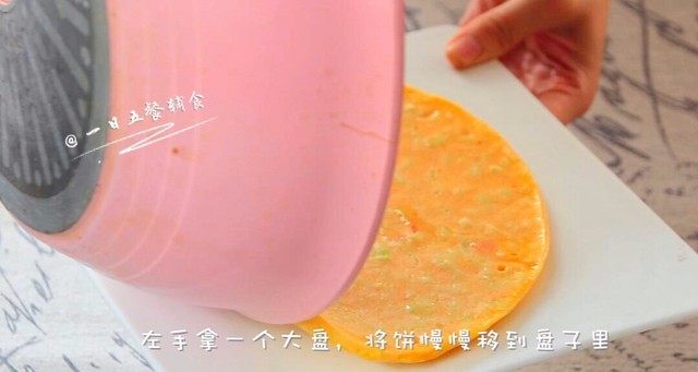 西瓜皮饼,左手拿一个大盘,将饼慢慢移到盘子里。