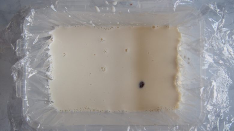 红豆奶油小方,晾凉后倒入铺有保鲜膜的容器中,放入冰箱中冷藏至凝固。