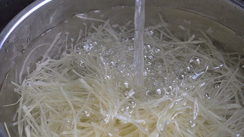 炝拌土豆丝,土豆丝入开水锅焯烫至断生。捞出用凉水冲洗,再过凉开水后控干水分备用。