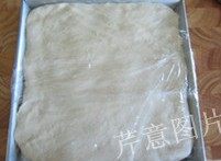 尼可拉可颂,将面团取出,在一个平盘中摊平,盖上保鲜膜,入冰箱冷冻1小时(以延缓面团发酵)