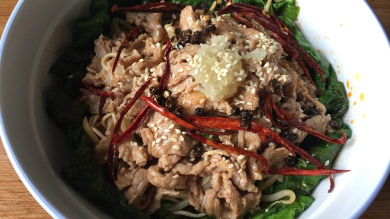 水煮肉片,捞出肉片放到菜里,放入之前煸炒过的辣椒丝、花椒,肉片最顶上放蒜泥,撒一些白芝麻;