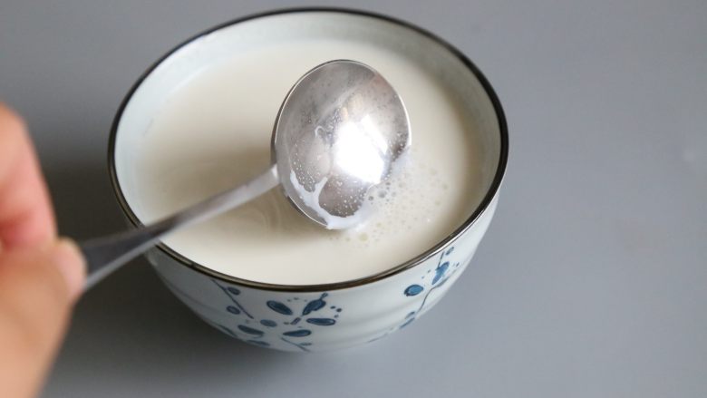 双皮奶,用勺子撇去泡沫后,让牛奶静至,表面产生奶皮。