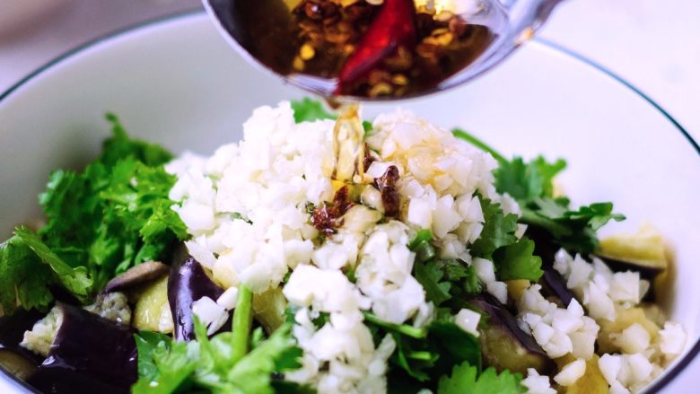 凉拌鱼香茄子,把香辣油趁热浇在蒜粒上，激出香味。