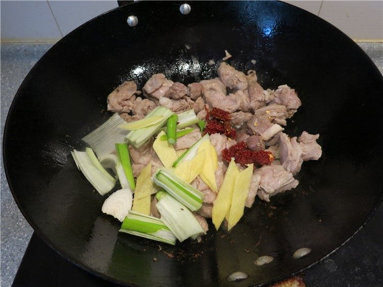 筋头巴脑胡萝卜烧羊肋条肉,水分收干时,将葱姜辣椒放入翻炒出香味