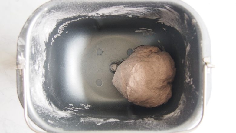 黑麦红枣核桃卷,加入清水,要根据面团的软硬程度进行适当调整,启动揉面程序,揉成光滑面团。