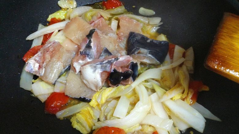 酸菜鱼,下入鱼骨,让鱼骨和酸菜一起翻炒。