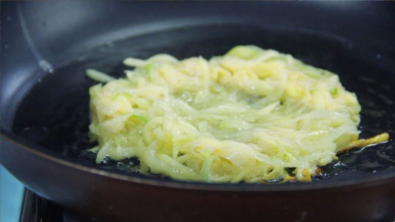 金黄香脆的土豆饼,好吃又简单!,煎制大约1分钟后可以看到土豆饼底部会有焦黄的颜色。