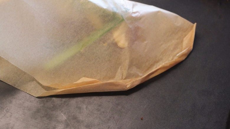 橙汁纸包鱼,将烤盘纸回折,边缘折出小小折痕。