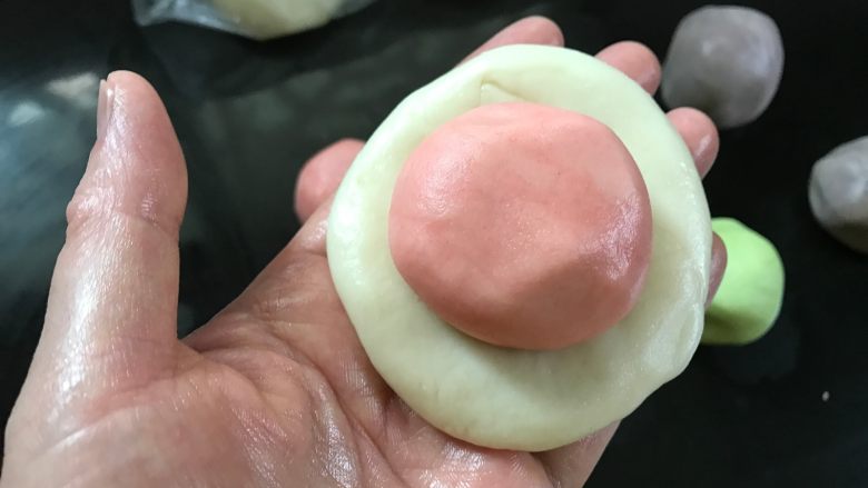 彩色螺旋蛋黄酥,把一个油皮面团按扁,放入一个油酥面团。