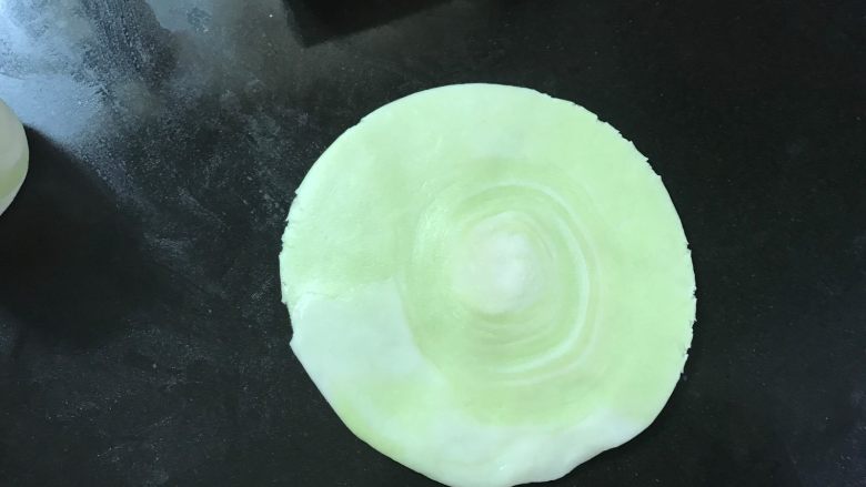 彩色螺旋蛋黄酥,把面卷一切为二,切面朝上擀成圆面片。