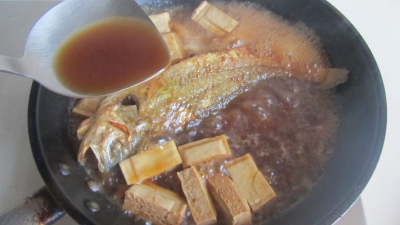 黄鱼焖豆腐,大火收汁,注意中间翻动一下鱼,将汤汁水不停地浇淋在鱼表面上;
