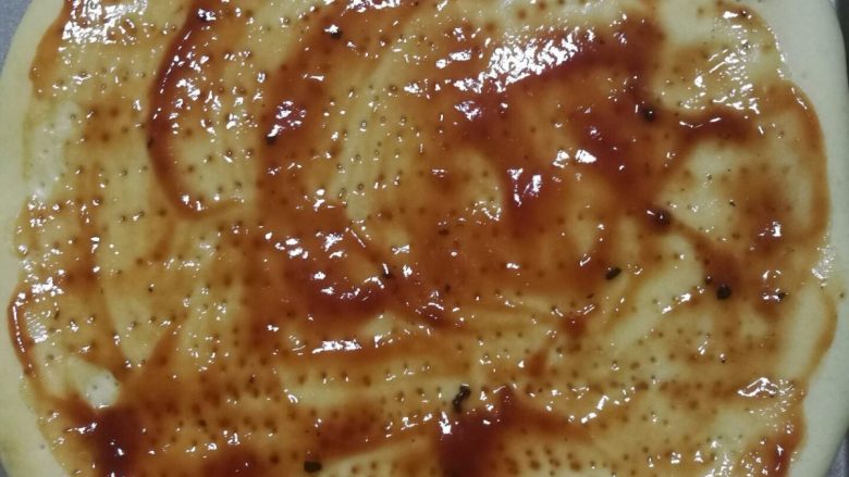 鲜虾火腿披萨,烤五分钟之后的披萨饼皮,拿出来上面涂上番茄酱或者披萨酱。