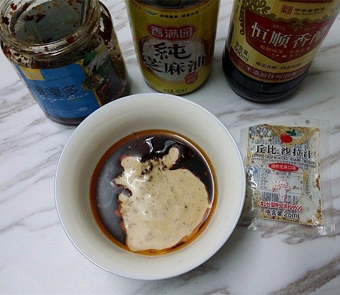 苦菊奶芙沙拉,碗中调入:食盐、白糖、鸡粉、香醋、麻油、牦牛肉酱和焙煎沙拉汁搅拌均匀