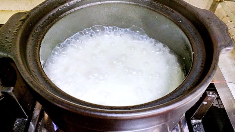香肠砂锅煲仔饭,听到砂锅煮开后,把砂锅盖打开,用木铲搅拌一下大米。