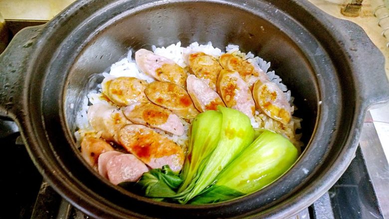 香肠砂锅煲仔饭,把汁水倒入煲仔饭里,盖上盖子。利用关火后的余温焖5分钟。5分钟后可以食用。