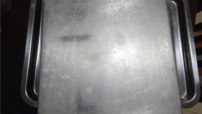 大理石蛋糕卷,蛋糕烘烤至表面金黄色后取出,轻震一下,用脱模刀四周划一圈,表面垫上油纸后倒扣在网架上(如有油纸,迅速将蛋糕片连同油纸拖出烤盘,置于晾架上),
