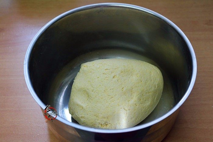 玉米面豆沙板栗包,慢慢加入温水,搅拌成大片雪花状的面絮,能成团时停止加水,揉成光滑柔软的面团,遮上保鲜膜,静置饧发20分钟左右