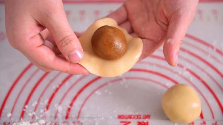 【烘焙配方】经典广式月饼,硅胶垫上撒少量粉,取一个小面团用手压扁,中间放一颗月饼馅