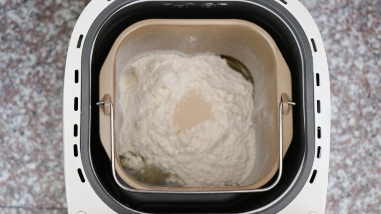 迷迭香佛卡夏,将面团中的所有食材按照先液体后固体的顺序放进面包机桶内,酵母放面粉中间,盐、糖对角放,选择和面功能;