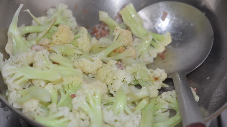 孜然花菜,比肉还好吃!,下入炒锅中,拌炒均匀。