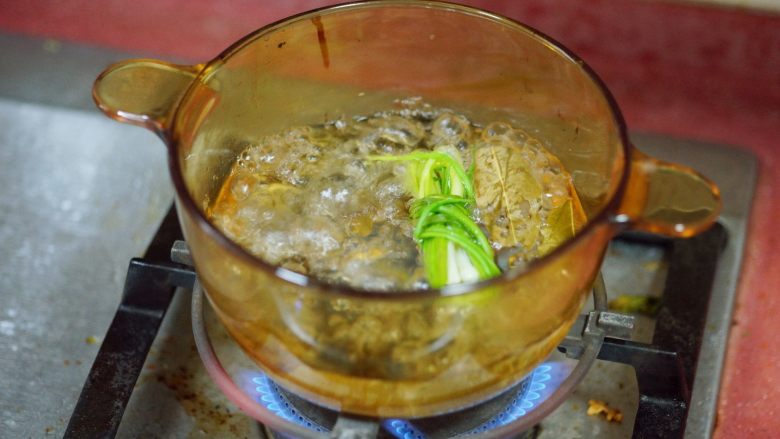 香辣秋葵手撕鸡,冷水开火,放入葱、生姜片,料酒,香叶,盖上盖子等水沸腾后,放入腌制好的鸡肉