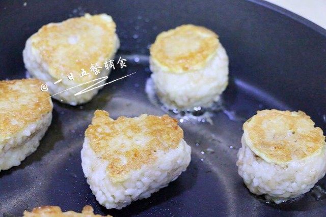 芝士蛋煎饭团,入锅,中火煎。 翻个面,煎一会调成小火,让里面的芝士和奶酪融化,薄薄的芝士融化很快的。