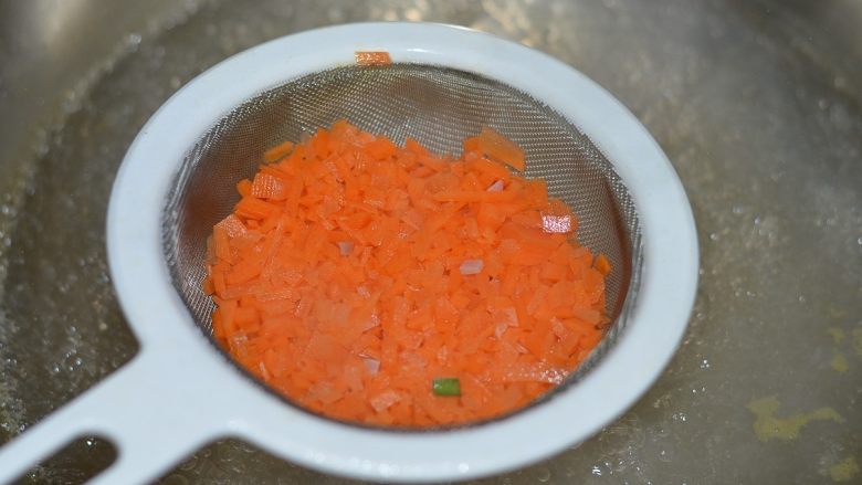 胡萝卜火腿煎蛋,越吃越爱,坐锅烧水,水开后用滤勺把胡萝卜焯水。因为太碎了,这样焯水比较省事儿是。