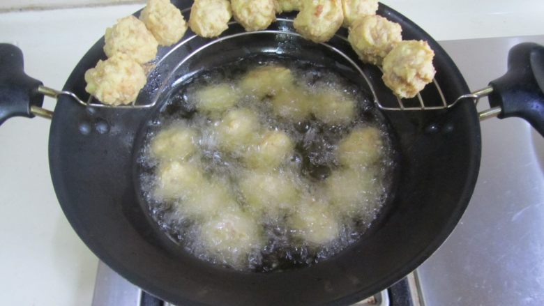 口蘑烩豆腐圆子,放入六、七成热的油中, 先中小火慢慢炸熟, 再大火复炸至金黄;