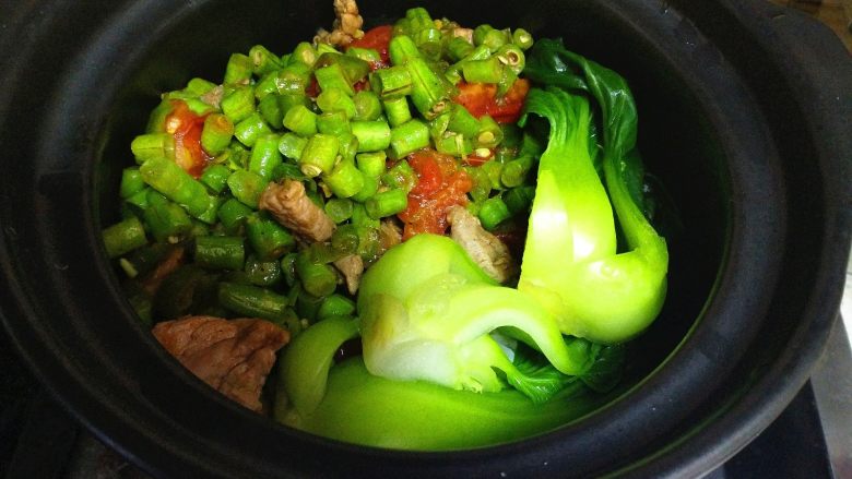 豆角煲仔饭,把洗净、焯水好的蔬菜放在米饭上,盖上砂锅盖焖2分后。