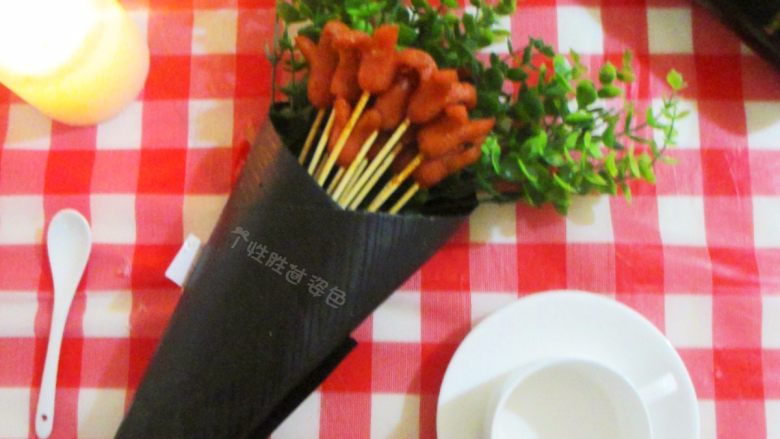 可以吃的花束——香辣香肠花束,把扎好的香肠放到黑卡纸上,加上一点绿色枝叶然后卷起来,尾端攥紧用丝带缠绕打结即可