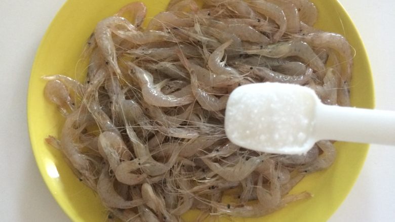 酥炸小河虾,撒入精盐,掂均匀进行腌制