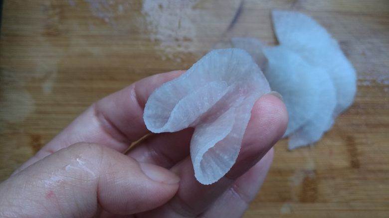 糖醋白萝卜,摆完一圈后,再拿起一片,先对折一次,再对折一次。