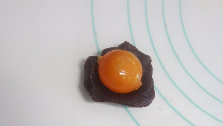 广式莲蓉蛋黄、豆沙蛋黄月饼制作方法,将称好的馅料搓圆压扁,我做了豆沙跟莲蓉两种馅料,放上咸蛋黄,用馅料把咸蛋黄包起,记住用虎口慢慢推,包裹均匀。最后揉圆。