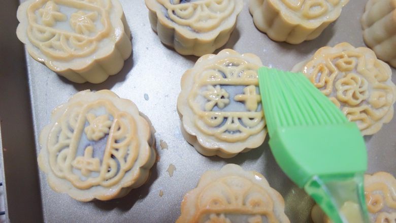 广式莲蓉蛋黄、豆沙蛋黄月饼制作方法,取出每次都晾凉5分钟,刷上蛋黄液+水(或全蛋液+水),记住表层蛋黄液别刷太多,最好用羊毛刷比较好控制蛋液量,蛋液只刷在花纹最上面凸出来的那部