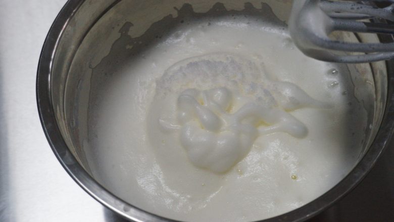 红丝绒奶油奶酪蛋糕,当提起打蛋器,蛋白低落出现纹路时,加入剩余⅓的细砂糖,改用中速搅拌