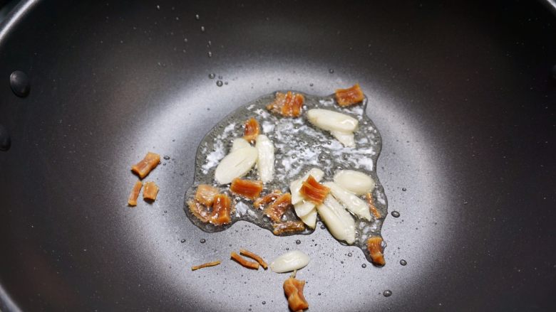 肉燥虾仁豆腐,下少量油,将干瑶柱和蒜片下锅干煸到发出香味。