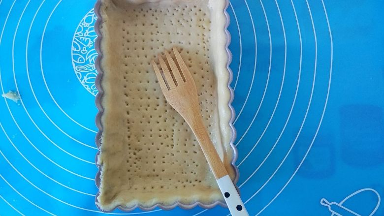 蜂蜜焦糖核桃派,用叉子把面皮叉出小孔,再在铺上锡纸压上重物170度上下火烤10分钟,面皮上色